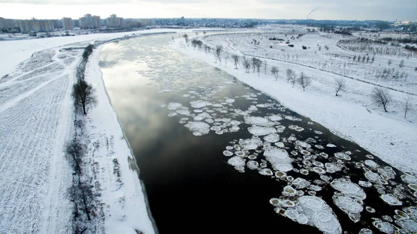 Ice swims in the river. Winter landscape photographed from above near the city. Top view. Nature and abstract background.