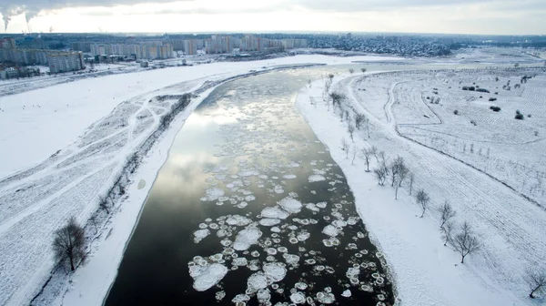 Ice swims in the river. Winter landscape photographed from above near the city. Top view. Nature and abstract background.