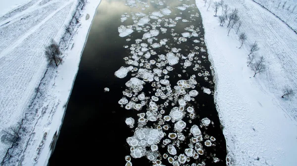 Ice swims in the river. Winter landscape photographed from above. Top view. Nature and abstract background