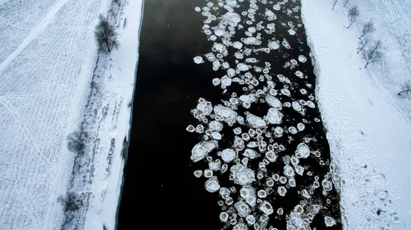 Ice swims in the river. Winter landscape photographed from above. Top view. Nature and abstract background