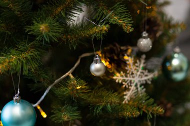 Toplar ve çelenklerle süslenmiş güzel yeşil Noel ağacı. Yakın plan fotoğraf. Parlak arkaplan