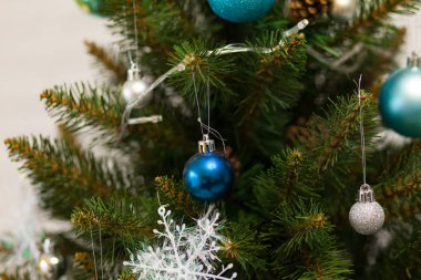 Toplar ve çelenklerle süslenmiş güzel yeşil Noel ağacı. Yakın plan fotoğraf.