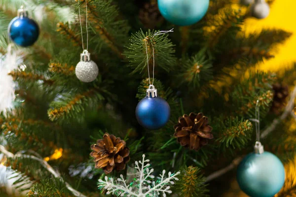 Toplar ve çelenklerle süslenmiş güzel yeşil Noel ağacı. Yakın plan fotoğraf. Sarı arkaplan — Stok fotoğraf