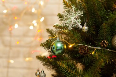 Toplar ve çelenklerle süslenmiş güzel yeşil Noel ağacı. Yakın plan fotoğraf. Parlak arkaplan
