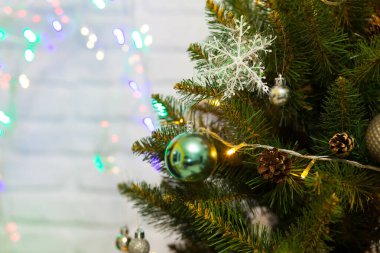 Toplar ve çelenklerle süslenmiş güzel yeşil Noel ağacı. Yakın plan fotoğraf. Parlak arkaplan