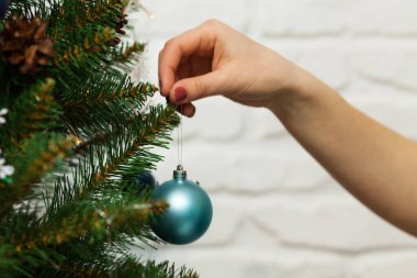 Kadın eli mutlu bir Noel ağacına güzel bir mavi top asar. Yakın plan fotoğraf.