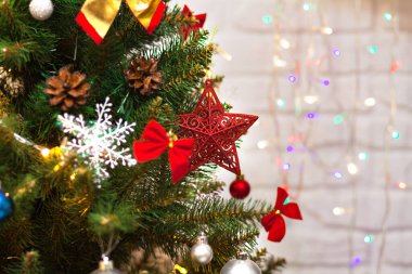 Toplarla süslenmiş güzel yeşil Noel ağacı, büyük kırmızı yıldız ve çelenkler. Yakın plan fotoğraf. Parlak arkaplan