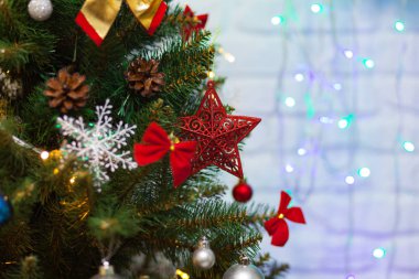 Toplarla süslenmiş güzel yeşil Noel ağacı, büyük kırmızı yıldız ve çelenkler. Yakın plan fotoğraf. Parlak arkaplan