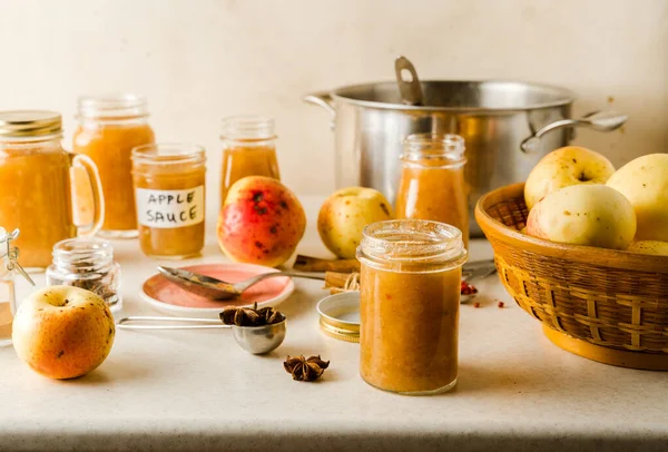 Cam kavanozlarda, malzemelerde, tabaklarda, mutfak masasında yeni pişirilmiş ev yapımı elma püresi. — Stok fotoğraf