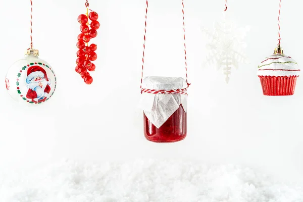 Zabawki świąteczne, czerwony dżem owocowy w szklanym słoiku, czerwone porzeczki wiszące na białym tle — Zdjęcie stockowe