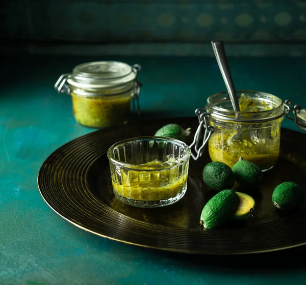 Homemade feijoa jam, fresh fruit on serving plate on teal colored background — Stock Photo, Image