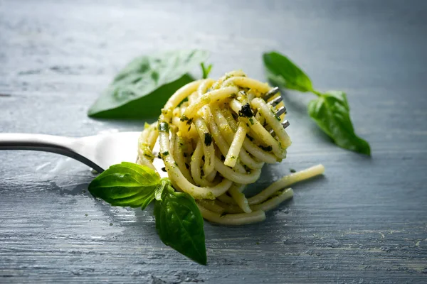 Servir espaguetis con pesto verde sobre tenedor con hojas de albahaca fresca — Foto de Stock