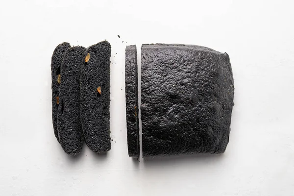Chleb brea węgiel drzewny częściowo w plasterkach, na białym tle — Zdjęcie stockowe
