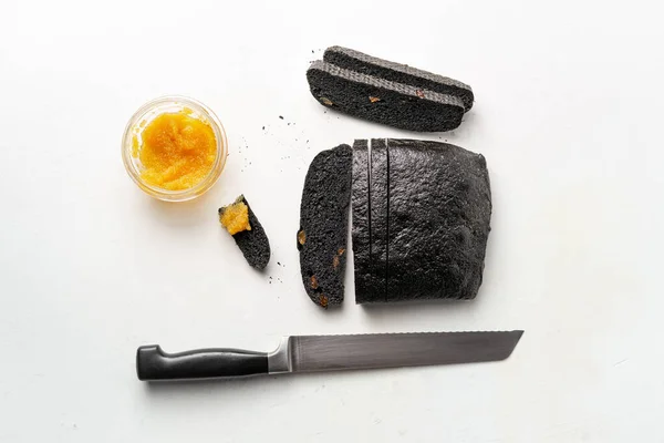 Hoja de brea de carbón parcialmente cortada, caviar de lucio, cuchillo de pan sobre fondo blanco — Foto de Stock