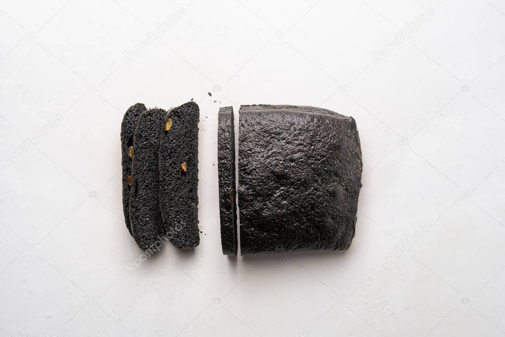 Loaf of charcoal brea partly sliced, on white background