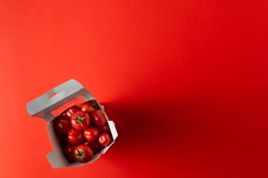 Kağıt üzerinde tatlı vişneli domatesler turuncu arka planda paket servis ediliyor.