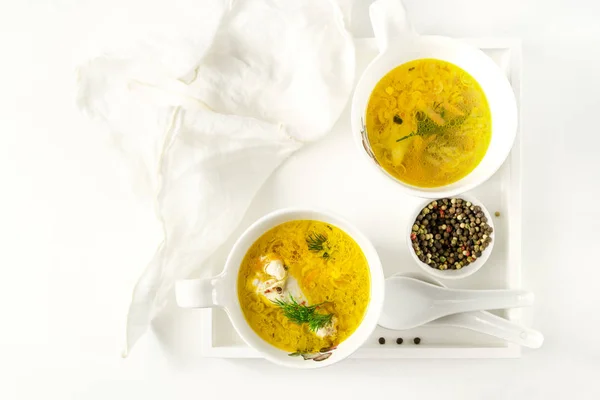 Homemade pasta chicken soup in bowls, ceramic spoons on a white tray with a napkin on white background — 스톡 사진