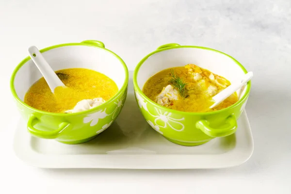 Homemade pasta chicken soup served in light green bowls with ceramic spoons on a white tray on white background — 스톡 사진