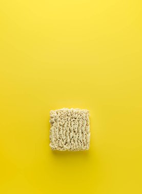 Canlı sarı arkaplanda kuru hazır erişte bloğu.