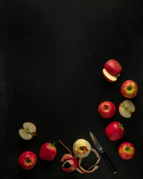 Pink lady apples, some cut with knife on black background with copy space — Stock Photo, Image