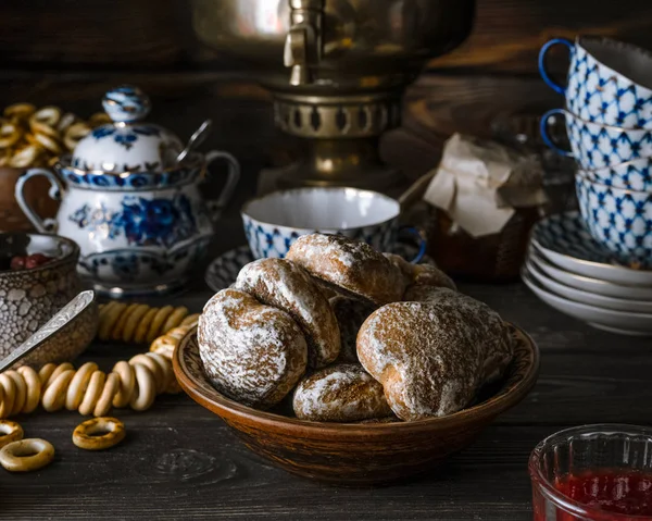 Traditional Russian tea table setup with gingerbread cookies, jam, bagels, tea kettle on dark rustic background. Closeup view, horizontal orientation