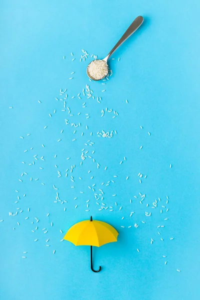 Granos Arroz Vertidos Cuchara Paraguas Juguete Amarillo Sobre Fondo Azul — Foto de Stock