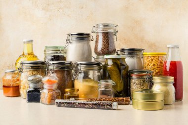 Tahıl, sos, domates sosu, cam şişe ve kavanozlardaki yağ, kuru makarna, mutfak masasında konserve. Sürdürülebilirlik kavramı. Yatay yönelim