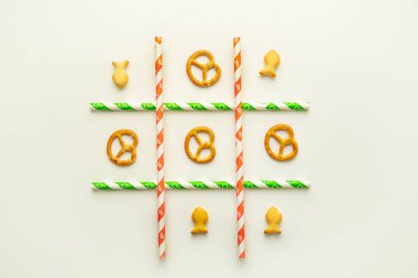 Küçük kuru krakerler ve beyaz arka planda pipet içen kağıt içeren Tic-tac-toe oyunu. Düz düzlem, yatay resim