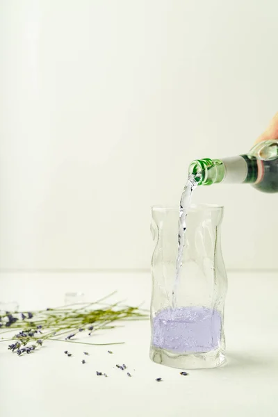 Jemand Gießt Lavendellimonade Aus Einer Flasche Highballglas Vor Weißem Hintergrund — Stockfoto