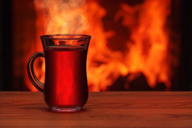 Bir şömine önünde masada bir çay bardağı