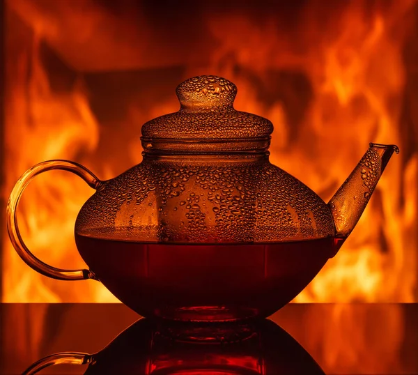 Eine gläserne Teekanne am Tisch vor dem Kamin — Stockfoto