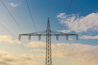 Günbatımı bulutlu gökyüzünde yüksek voltaj mast silueti