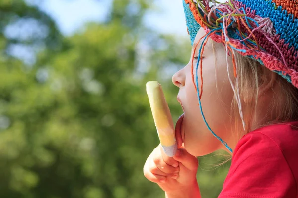 かわいい女の子は夏の晴れた日に公園でアイスクリームを舐めています。 ロイヤリティフリーのストック画像