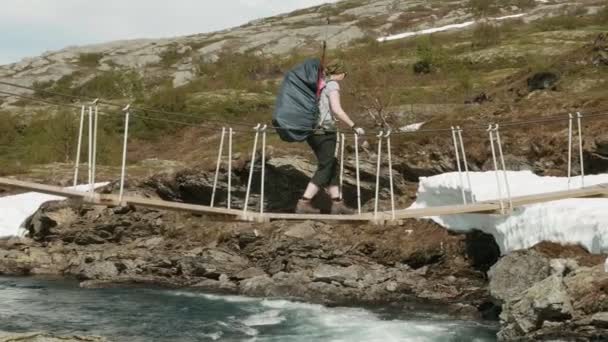 Niña en el puente a través del río de montaña en Noruega — Vídeo de stock