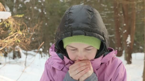 Chica joven calienta las manos en el frío bosque de invierno — Vídeos de Stock