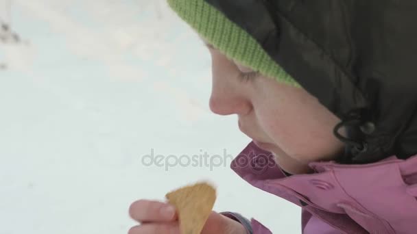 Young girl eats chips in the winter forest — Stock Video