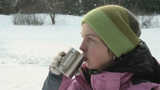 Девушка пьет кофе на улице зимой — стоковое видео
