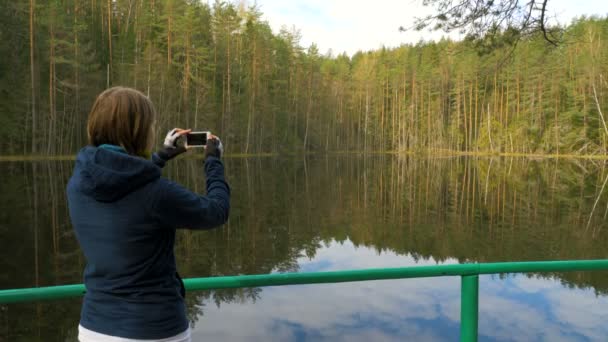 Flicka gör en bild med telefonen i skogen — Stockvideo