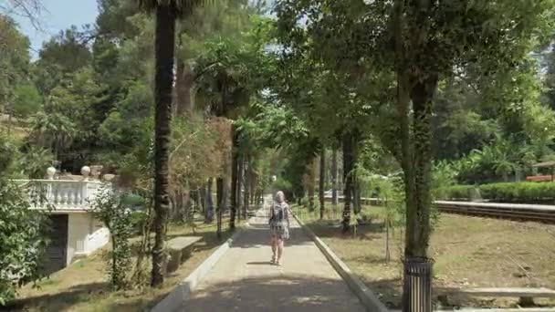 Junges Mädchen, das die Palmenallee entlanggeht. batumi botanischer Garten, Georgien — Stockvideo