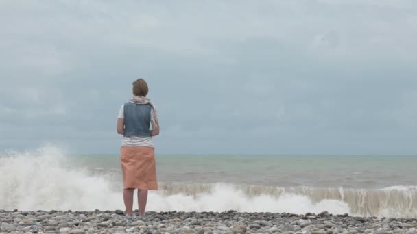 Ung flicka på stranden titta på höga vågor i havet - Georgien — Stockvideo