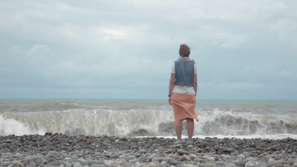 Ung flicka på stranden titta på höga vågor i havet - Georgien — Stockvideo