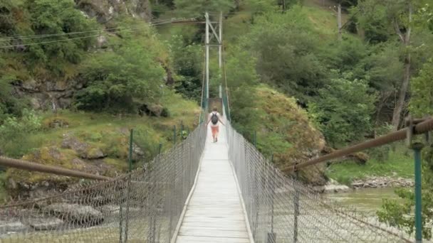 Chica joven camina en el puente colgante - Georgia — Vídeos de Stock