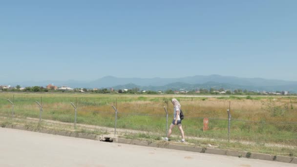 Jong meisje wandelingen langs de prikkeldraad hek van luchthaven. Batumi, Georgië — Stockvideo