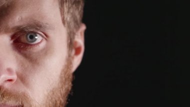 Genç bir adam siyah bir zemin üzerine bir stüdyoda ciddi göz