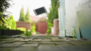 Cep telefonu yavaş çekimde beton zemine düşüp kırılıyor.