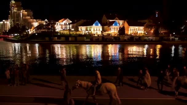 Mensen wandelen op het toeristische gebied Nemiga van de nachtstad Minsk langs de rivier — Stockvideo