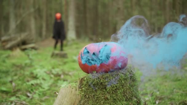 Person geht maskiert und kokettiert an Halloween mit Räucherkürbis im Wald — Stockvideo