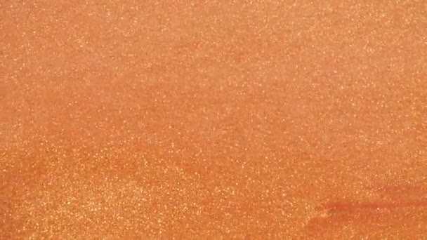 Sable doré coloré se déplace organiquement dans un liquide coloré en macro 