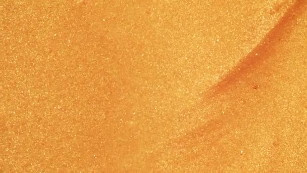 Sable doré coloré se déplace organiquement dans un liquide coloré en macro 