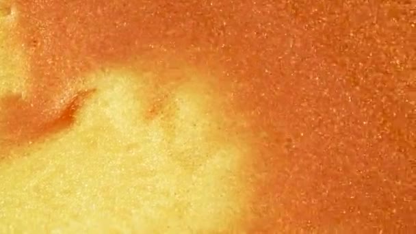 Sable doré coloré se déplace organiquement dans un liquide coloré en macro 